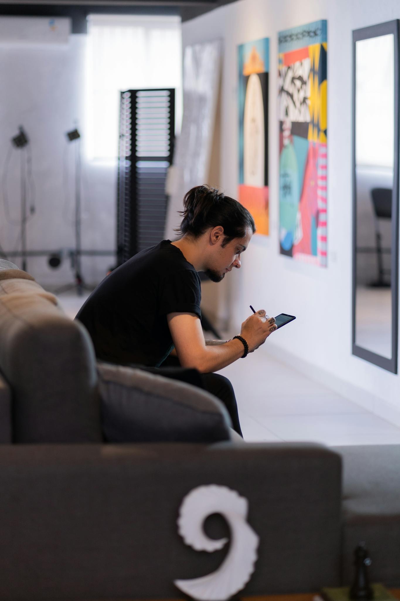 A man interacts with his smartphone in a contemporary art studio, surrounded by vibrant posters.